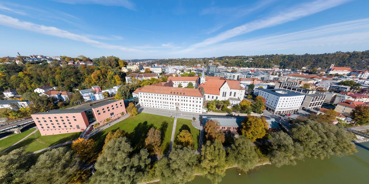 An  aerial photo of the university of Passau's campus with the city of Passau behind it
